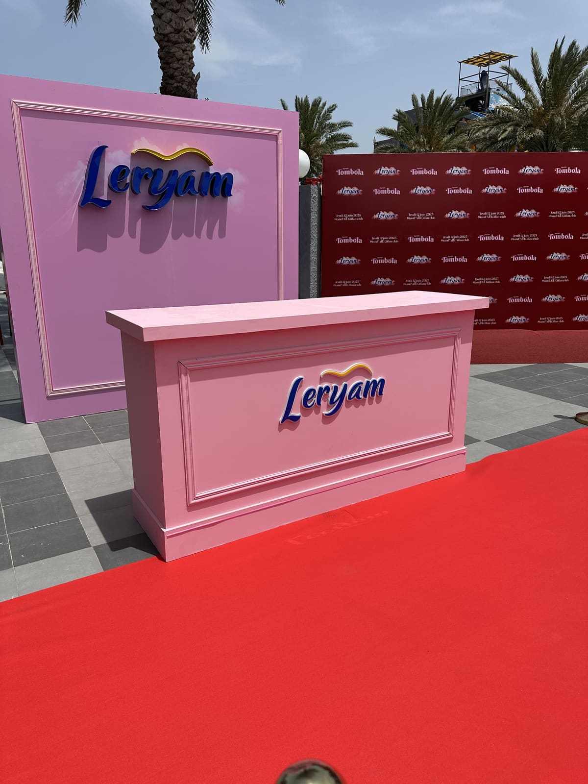 Comptoir d'accueil Leryam et mur de marque en extérieur, à côté du tapis rouge