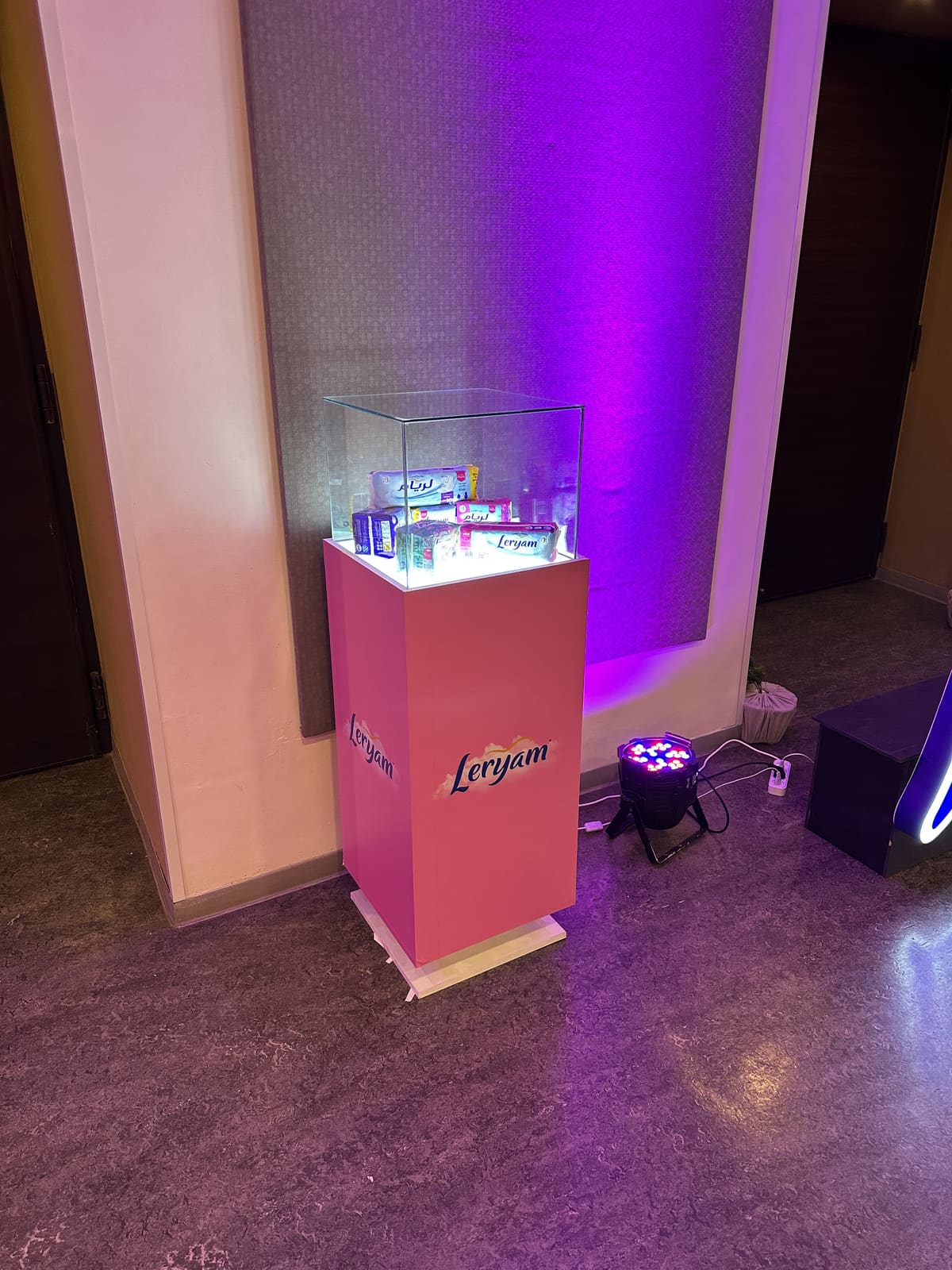 Vitrine en verre rétroéclairée présentant les produits Leryam sur socle rose