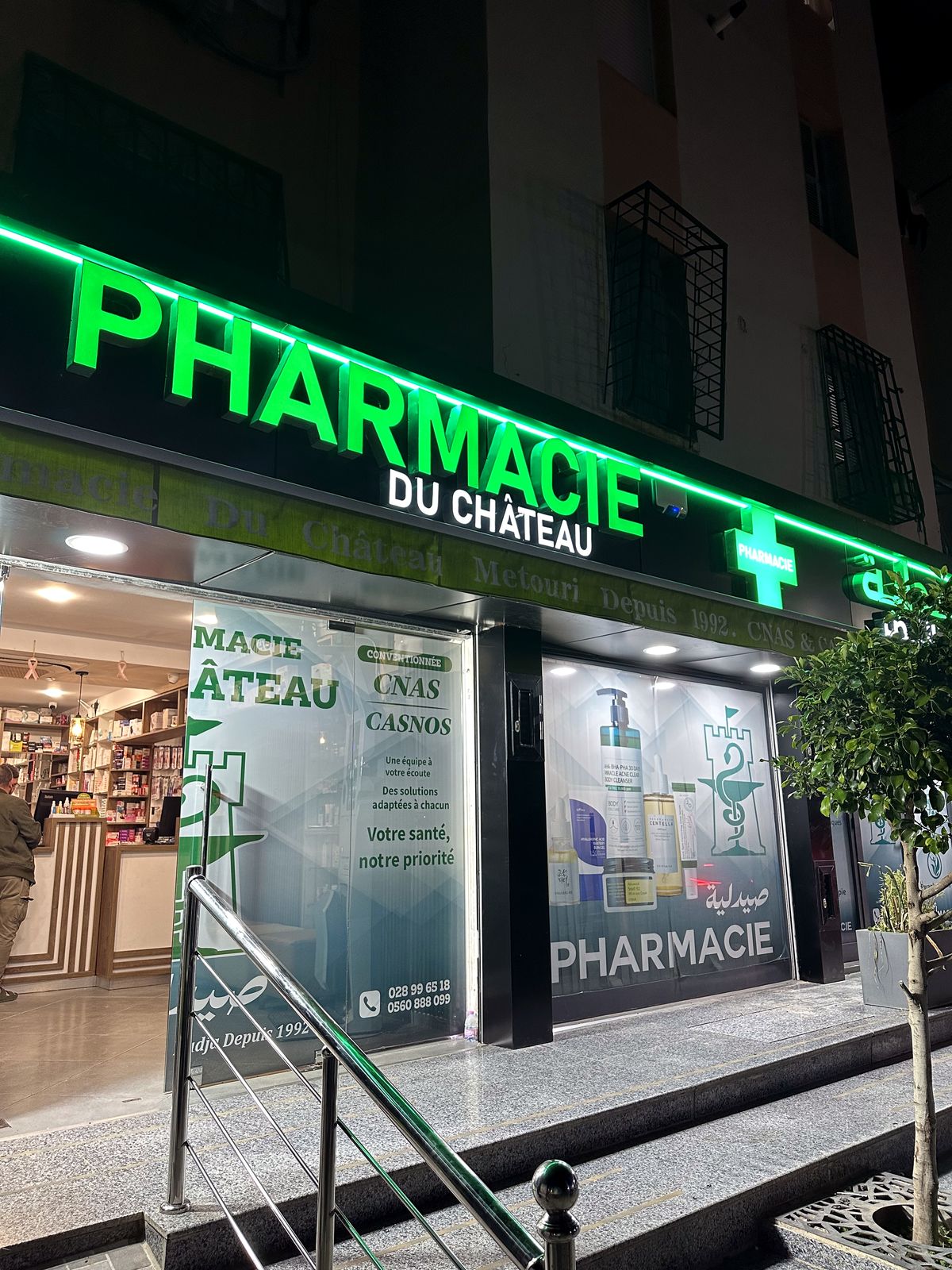 Enseigne lumineuse verte de la Pharmacie du Château à Alger, vue de nuit