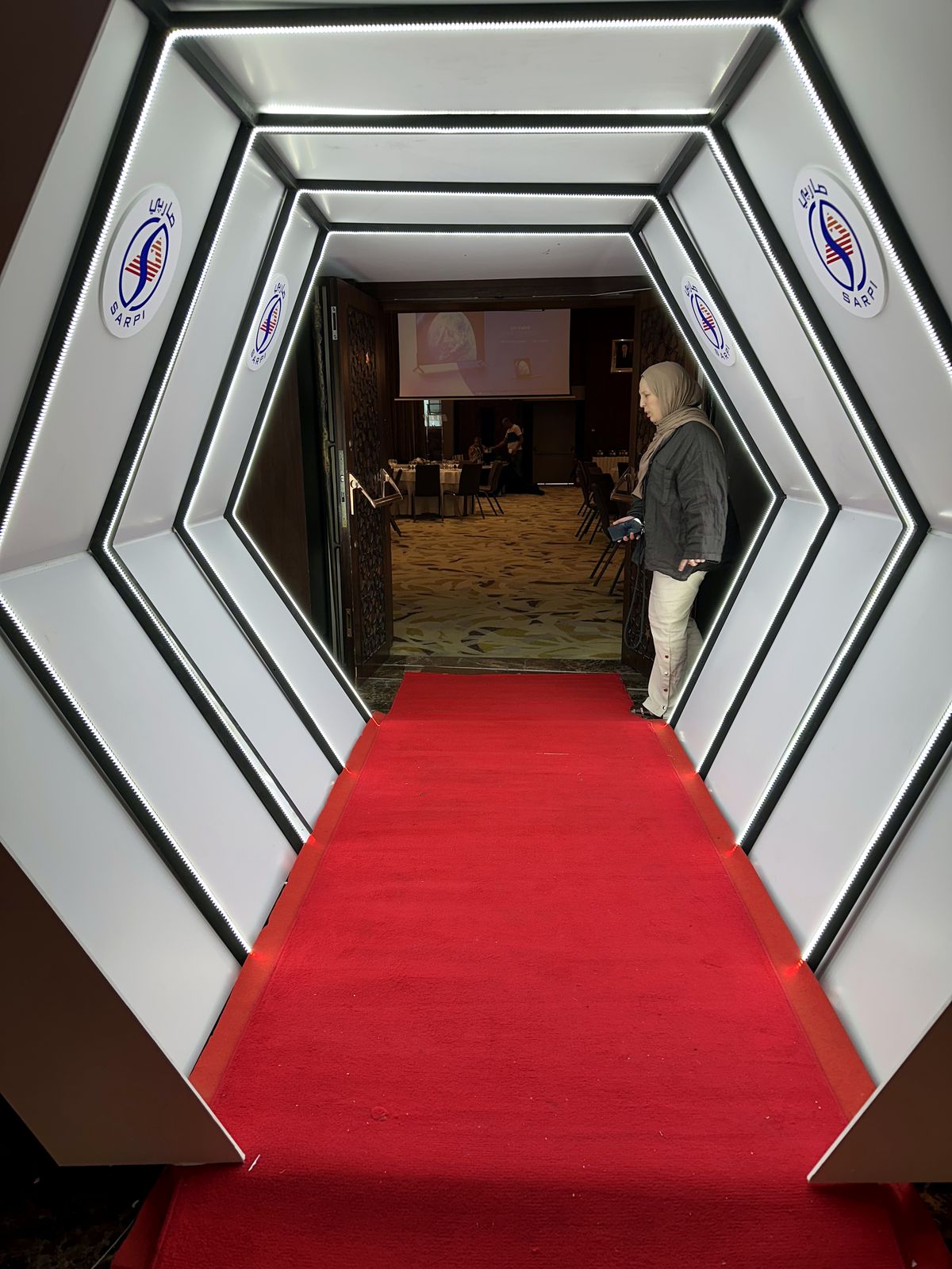 Tunnel d'entrée en arches hexagonales rétroéclairées, tapis rouge, cérémonie SARPI à Alger