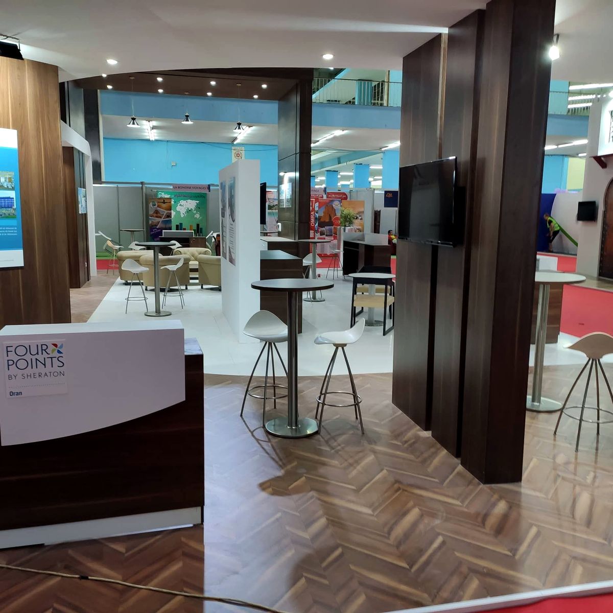 Espace intérieur du stand hôtelier avec mange-debout et écrans